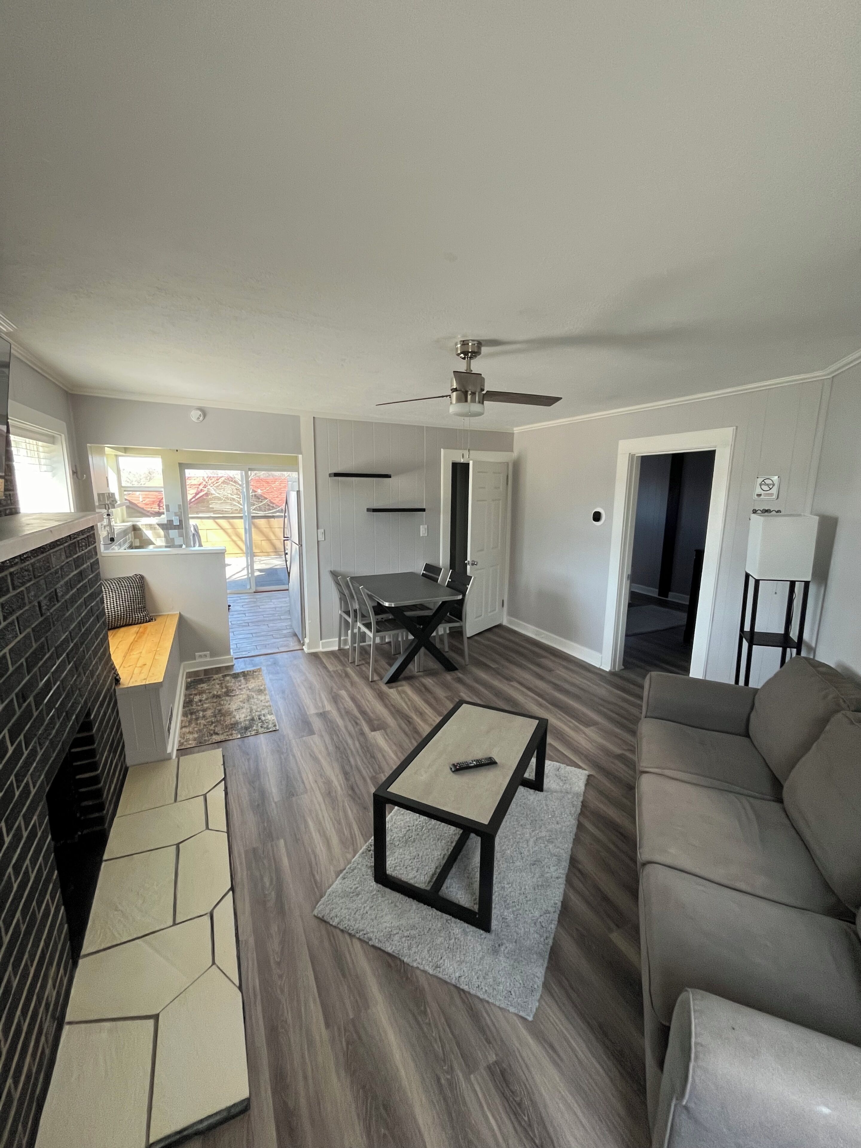 A living room with a fireplace, a sofa, a coffee table, and a dining area with chairs.