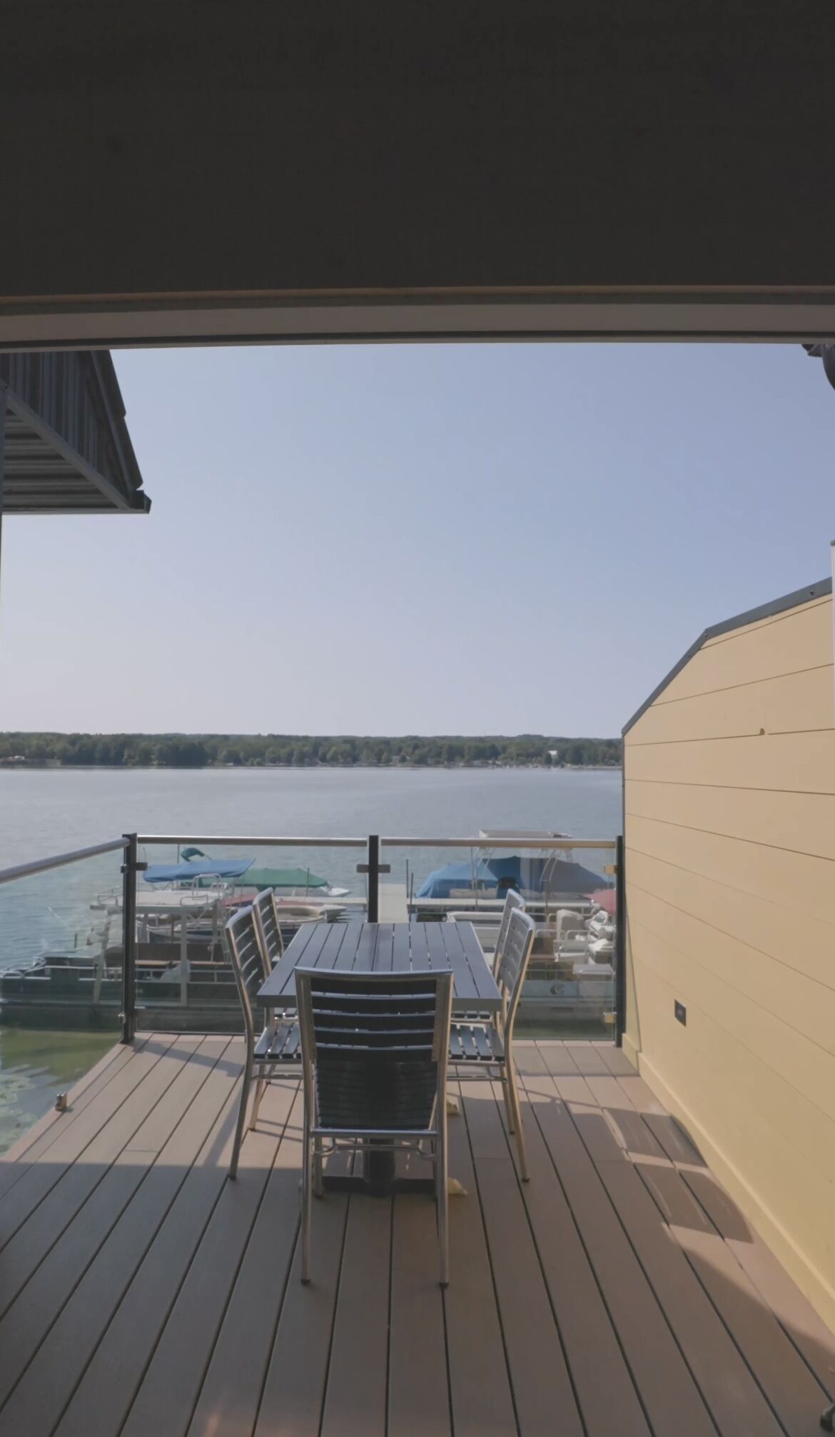 Een terras met tafel en stoelen, met uitzicht op een jachthaven met boten.