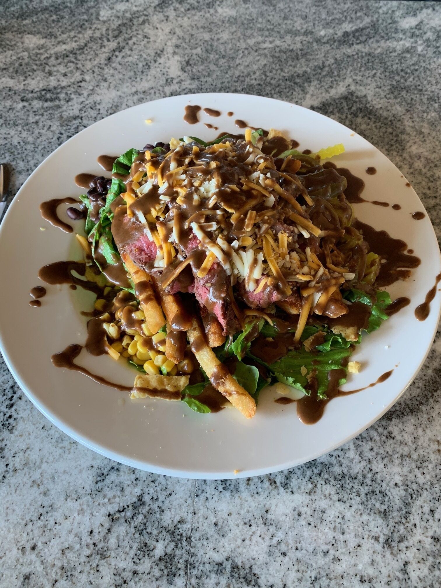 Un plato de comida con bistec, papas fritas y ensalada.