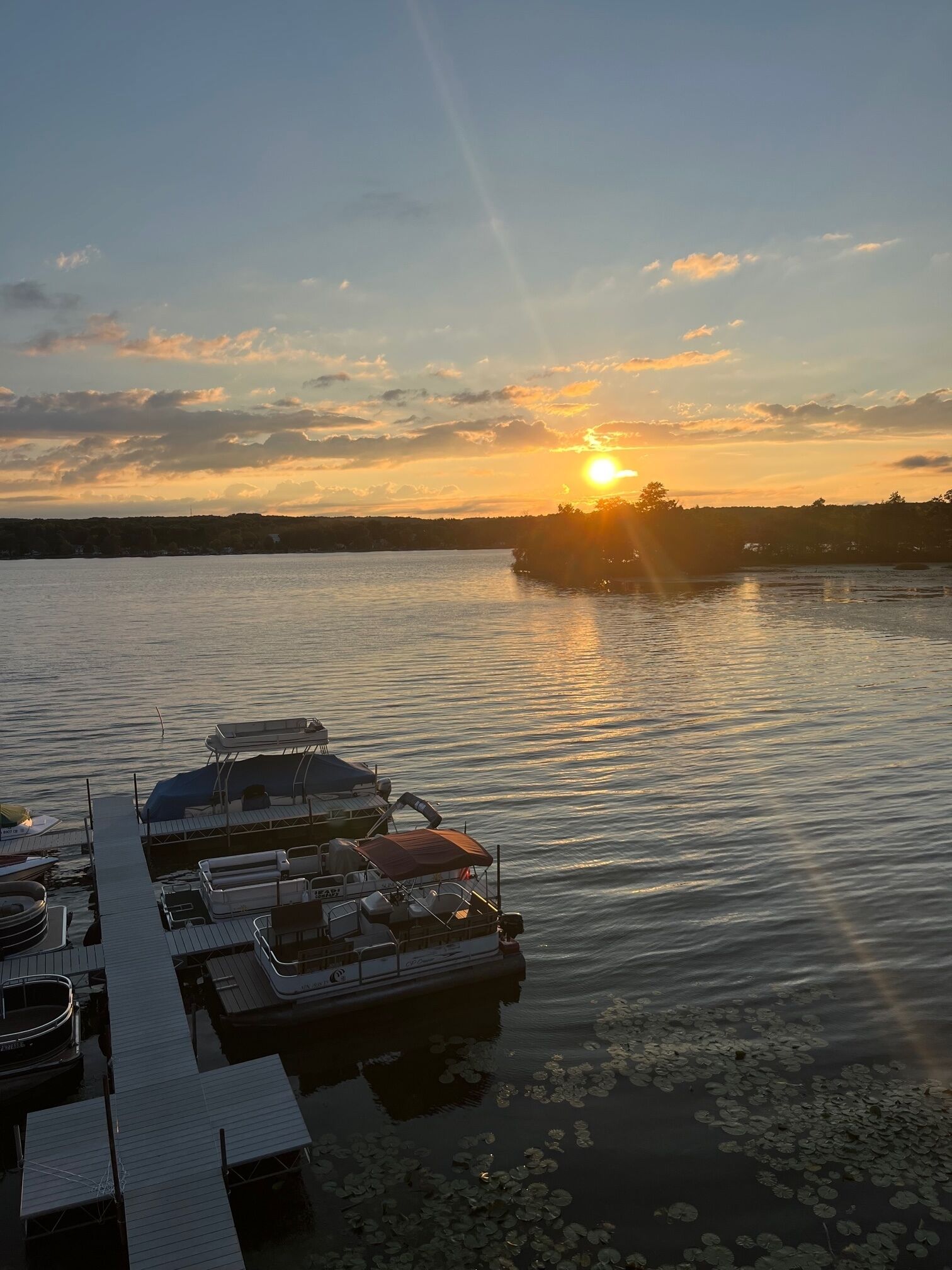 Een jachthaven met aangemeerde boten en een ondergaande zon op de achtergrond.
