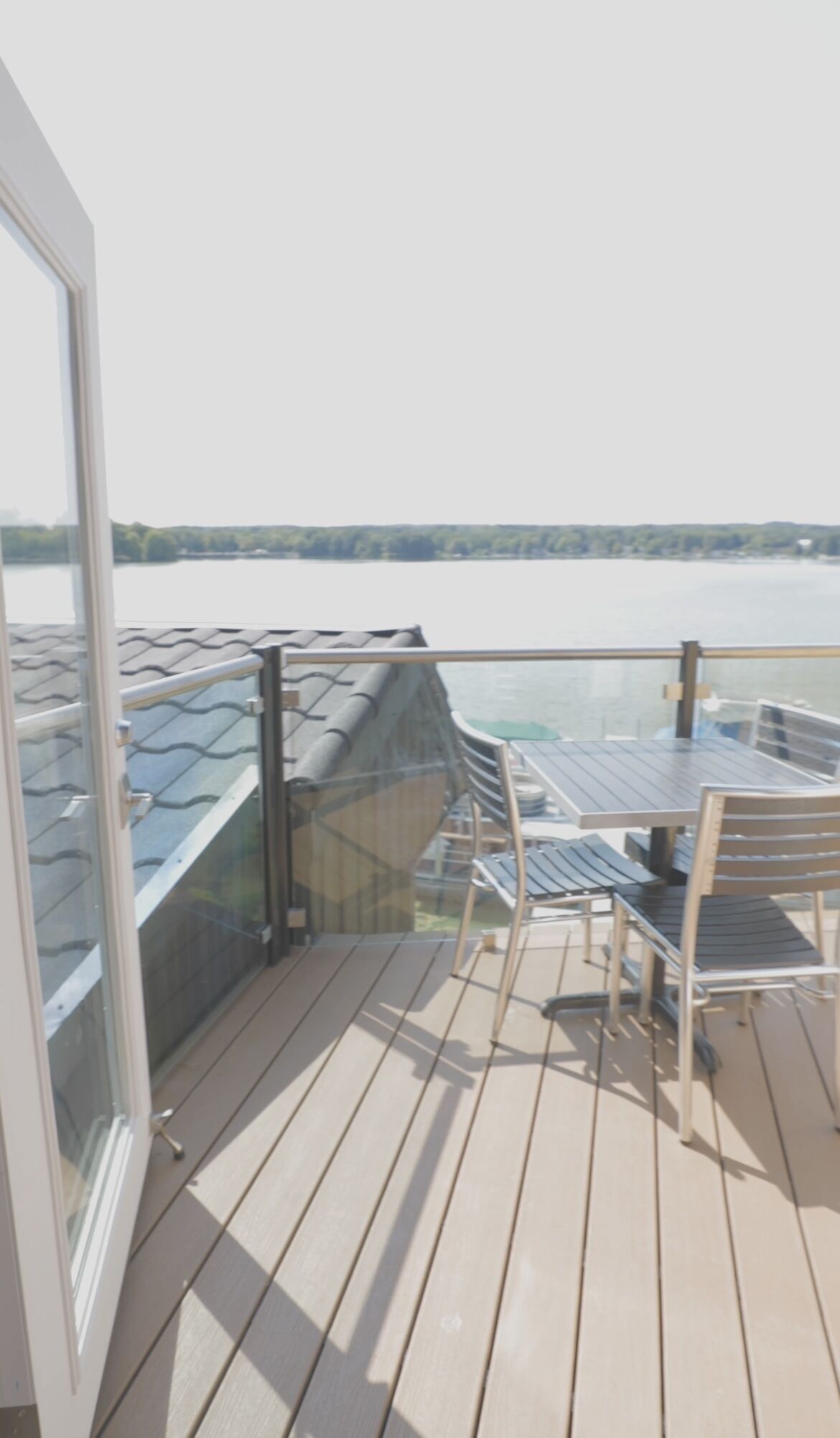 En balkon med udsigt over vandet, et bord og stole.
