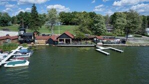 A lakeside property with docked boats, a covered seating area, and a building with a red roof. - Edinboro Lake Resort Cabins (Edinboro)