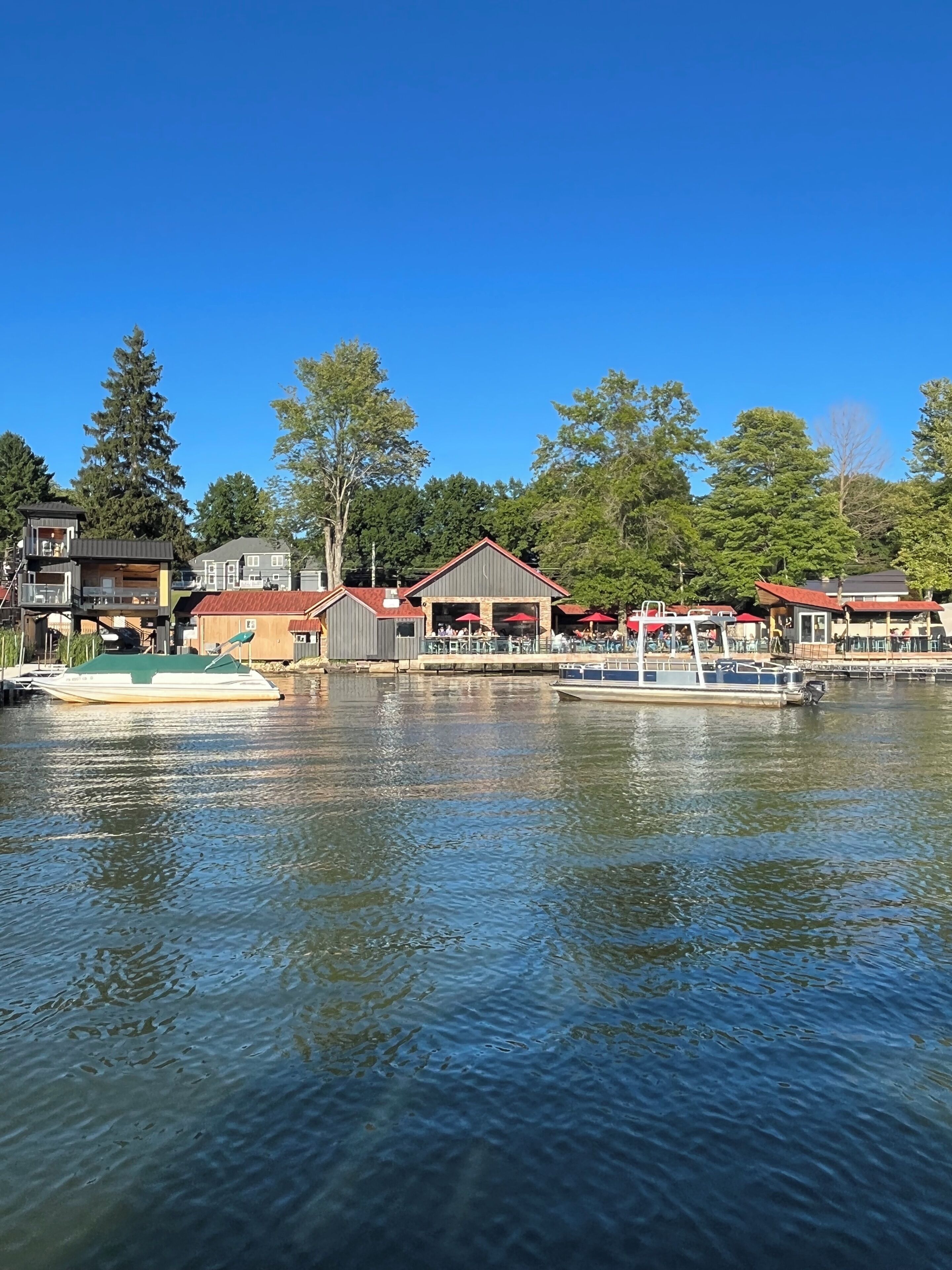 A waterfront property with a dock, a small building with a red roof, and a boat.