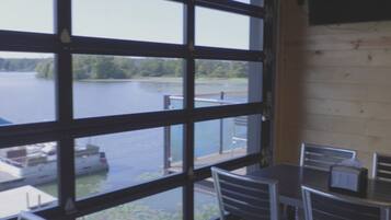 A room with large windows overlooking a lake, metal chairs, and a table.