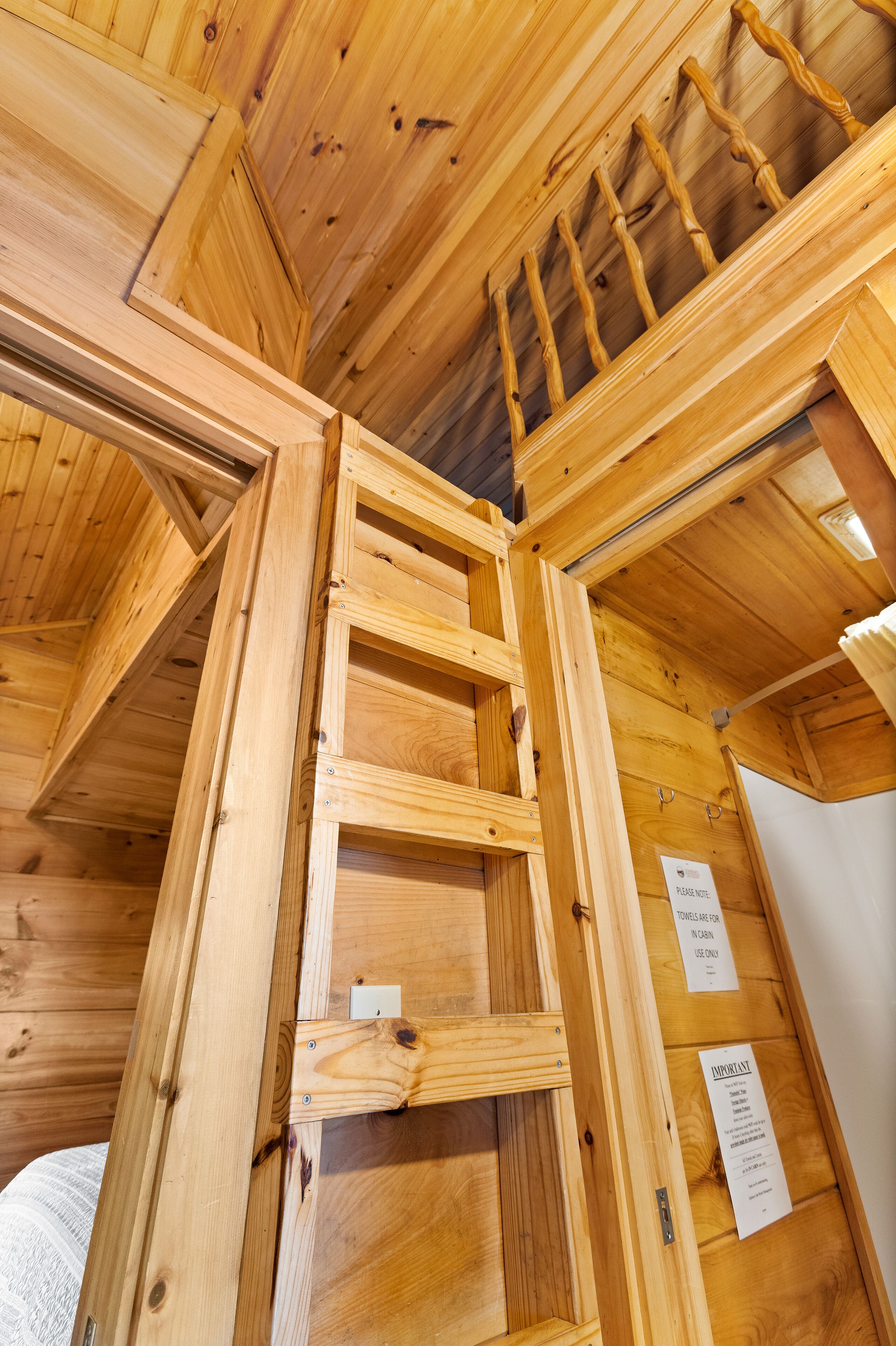 Interior de madera con un entrepiso para dormir y una escalera.