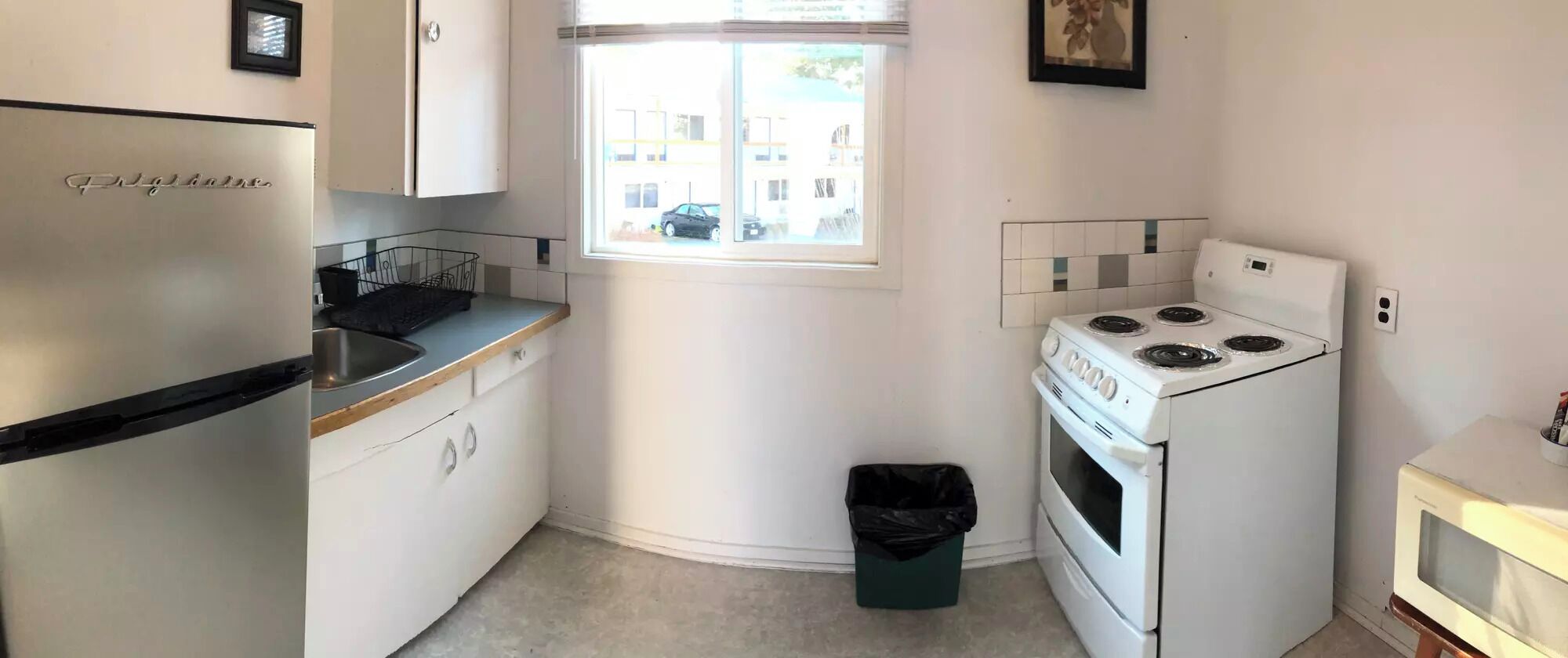 A compact kitchen with a refrigerator, stove, and microwave.