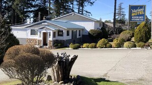 A Marland Motel with a stone facade, a single entrance, and a sign indicating modern kitchenettes. - Marland Motel (Powell River)