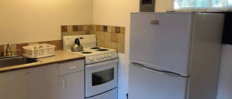 A compact kitchen with a gas stove, oven, and a refrigerator.
