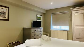 A hotel room with a bed, a dresser, a television, and a window with a blind.