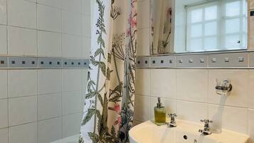 Ein Badezimmer mit einem weißen Waschbecken, einem Spiegel und einer Duschvorhang mit Blumenmuster.