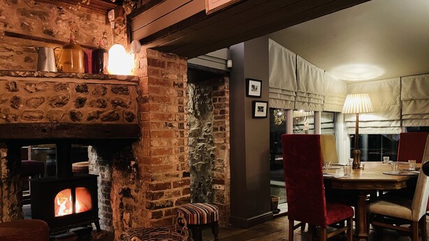 A cozy room with a stone fireplace, a dining table with chairs, and a wicker basket.
