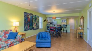 Un salon comprenant un canapé, un fauteuil et un coin repas avec des chaises et une table.