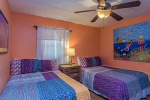 A bedroom with two beds, a ceiling fan, a window with curtains, and a painting on the wall. - Beachview by South Padre Condo Rentals (South Padre Island)