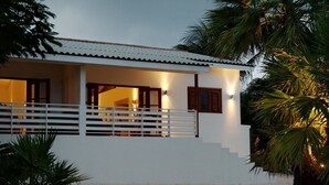 A white building with a balcony, a staircase, and a palm tree in the foreground. - Bantopa Apartments & Villas (Sint Michiel)