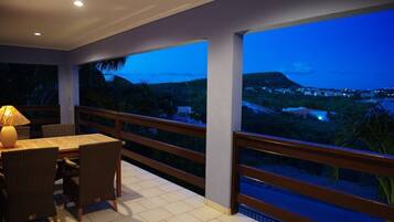 Ein Balkon mit Tisch und Stühlen, der auf eine reizvolle Landschaft im Zwielicht blickt.