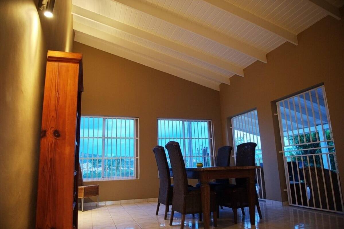 Comedor con techo alto, ventanas grandes y vista al exterior.