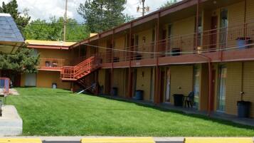 A motel with a two-story structure, a staircase leading to the upper level, and a well-maintained lawn in front.