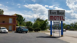 A motel sign with a clear view of the surrounding parking area and a building in the background. - Essex House Motel (Littleton)