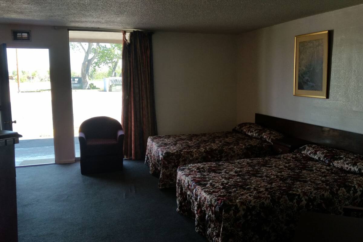 Ein Hotelzimmer mit zwei Betten, einem Sessel und einem Bild an der Wand.