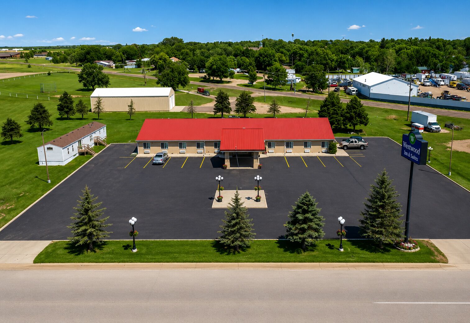 A hotel with a red roof, a parking lot, and a sign indicating it is a Westwood Inn & Suites.