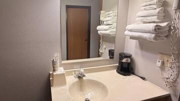 A hotel bathroom with a sink, mirror, towel rack, and a hairdryer.