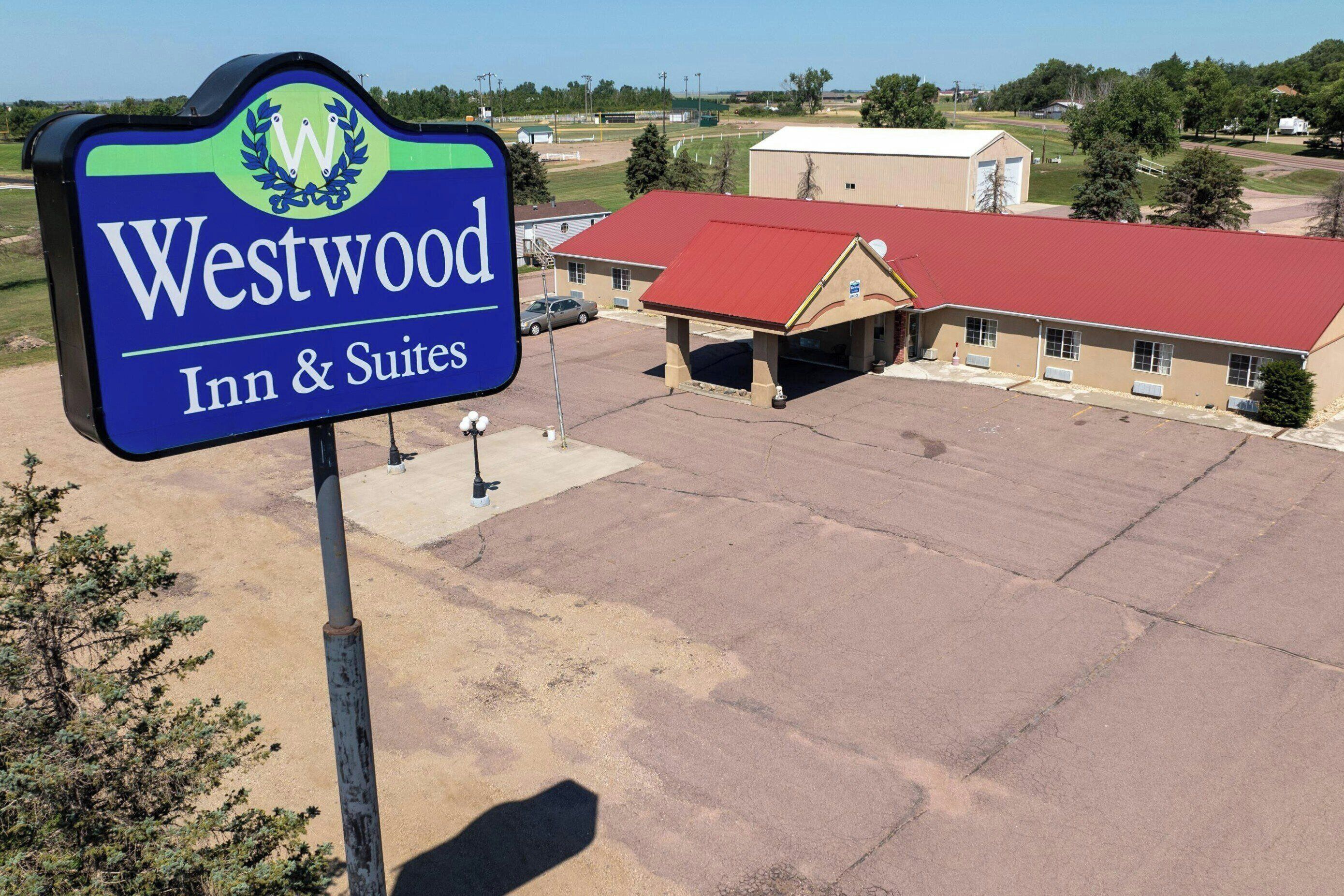 A Westwood Inn & Suites sign with a red-roofed building in the background.