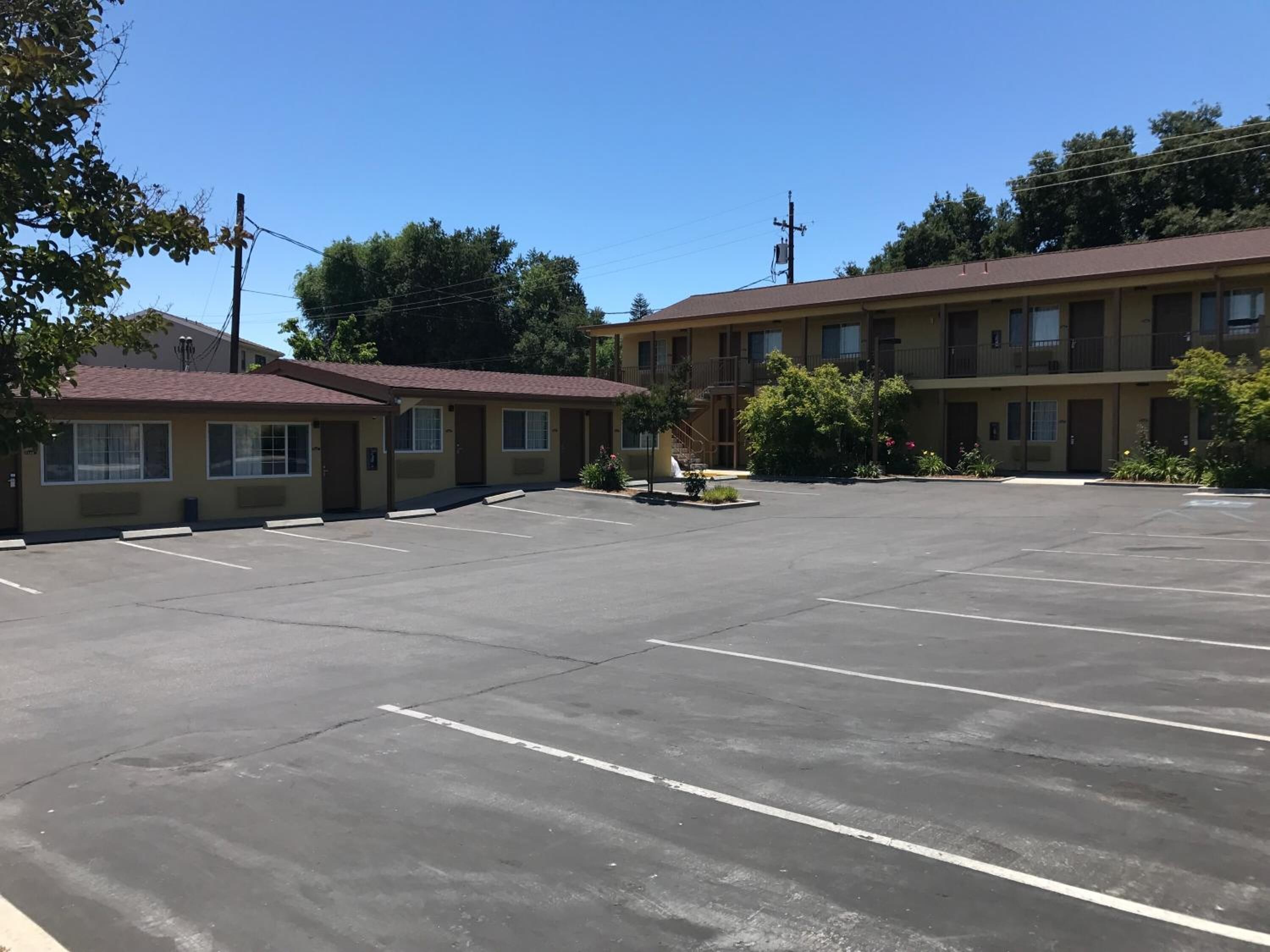 A motel with a parking lot, multiple motel units, and a small outdoor seating area.