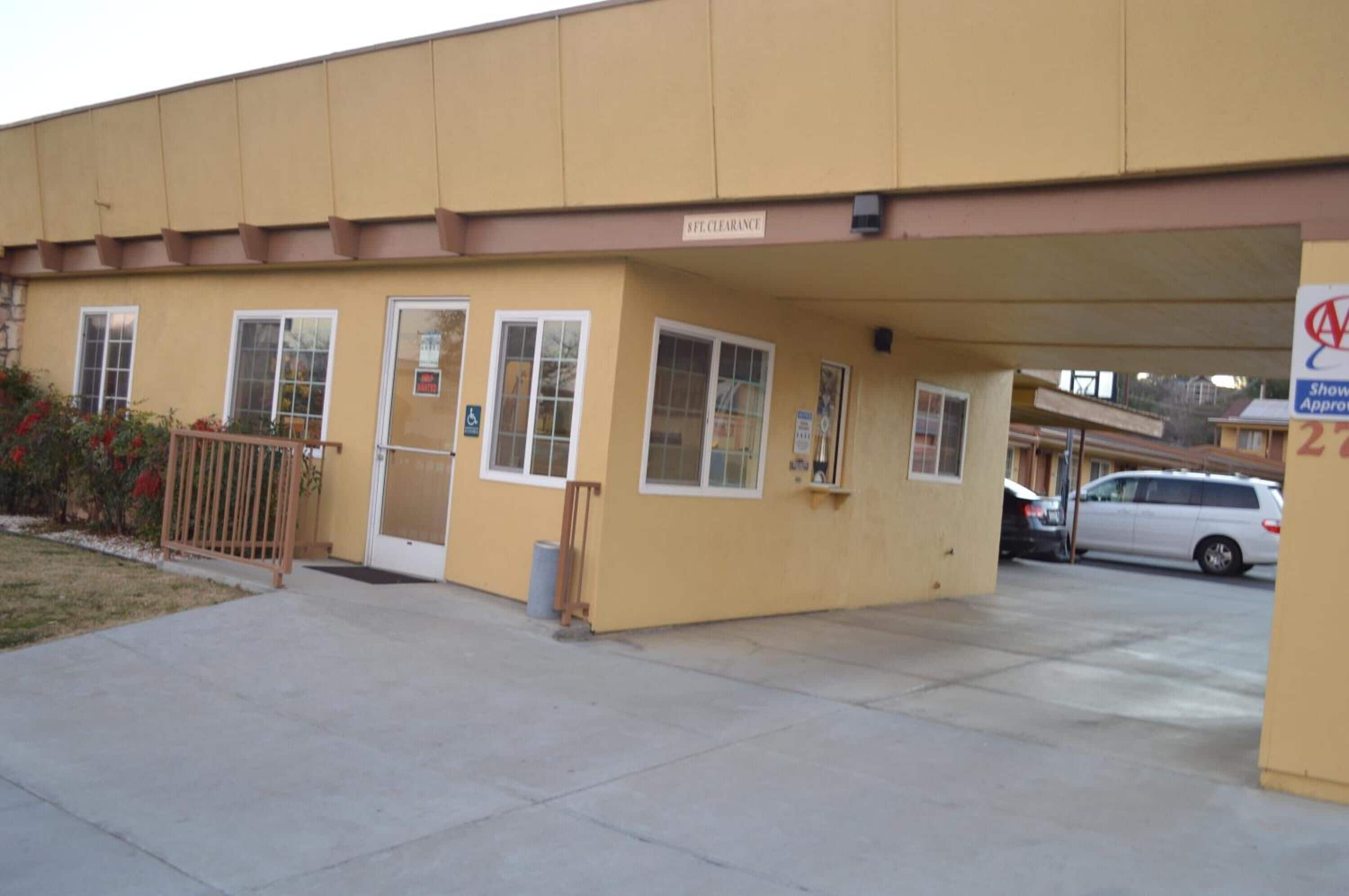 A building with a beige exterior, a sign indicating '6th Floor', and a covered parking area.