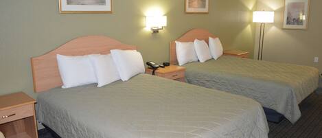A hotel room with two beds, bedside lamps, and a nightstand with a phone.