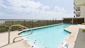 Una piscina con una escalera de metal, un letrero con el número 3 y vista a la playa.