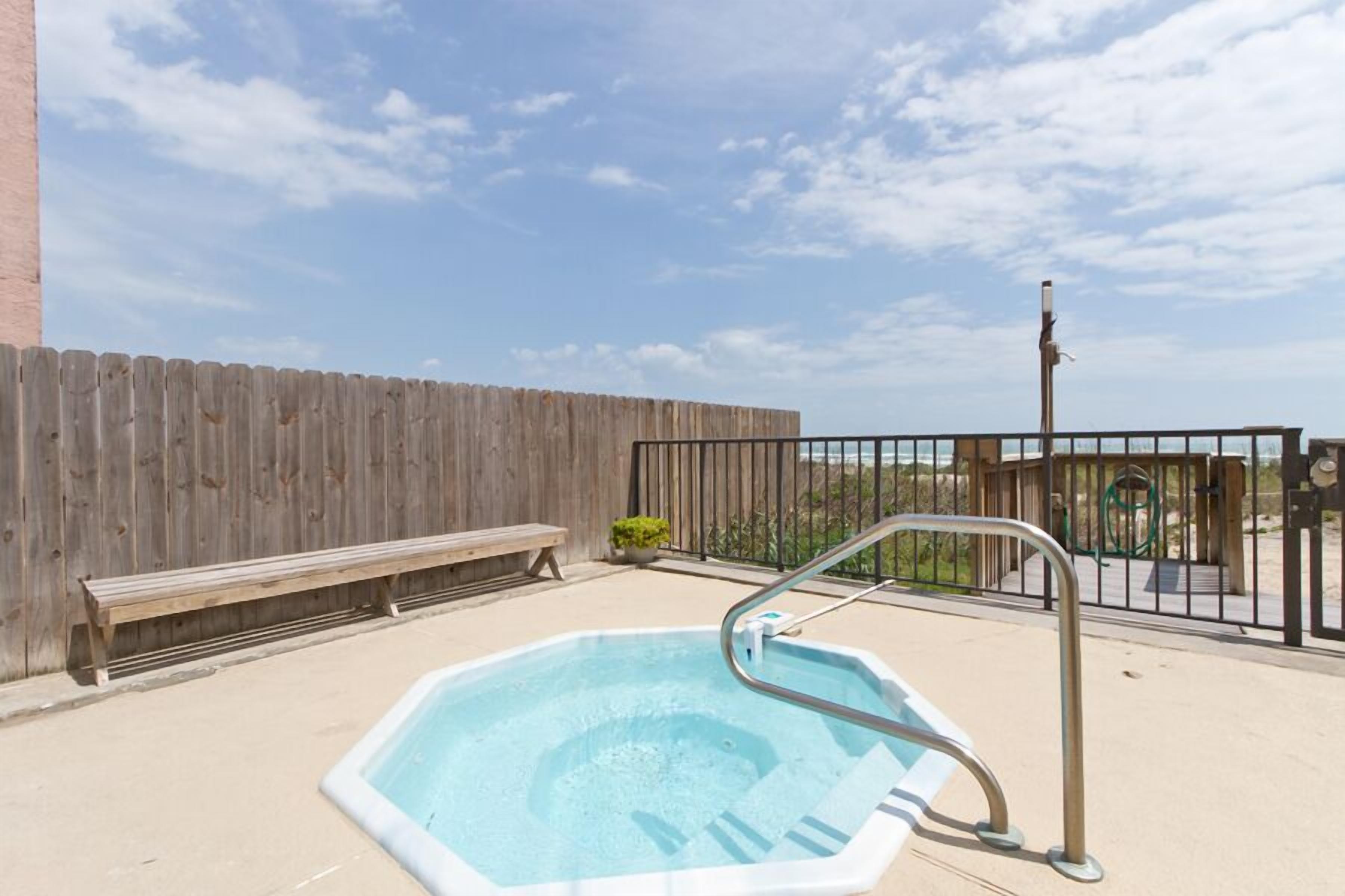 A hot tub with a metal ladder, a wooden bench, and a wooden fence in a backyard setting.