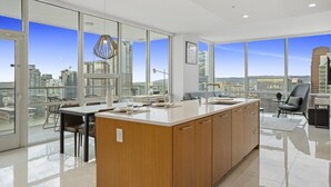 A modern kitchen with a large island, large windows, and a city view. - Level Los Angeles Downtown - South Olive (Los Angeles)