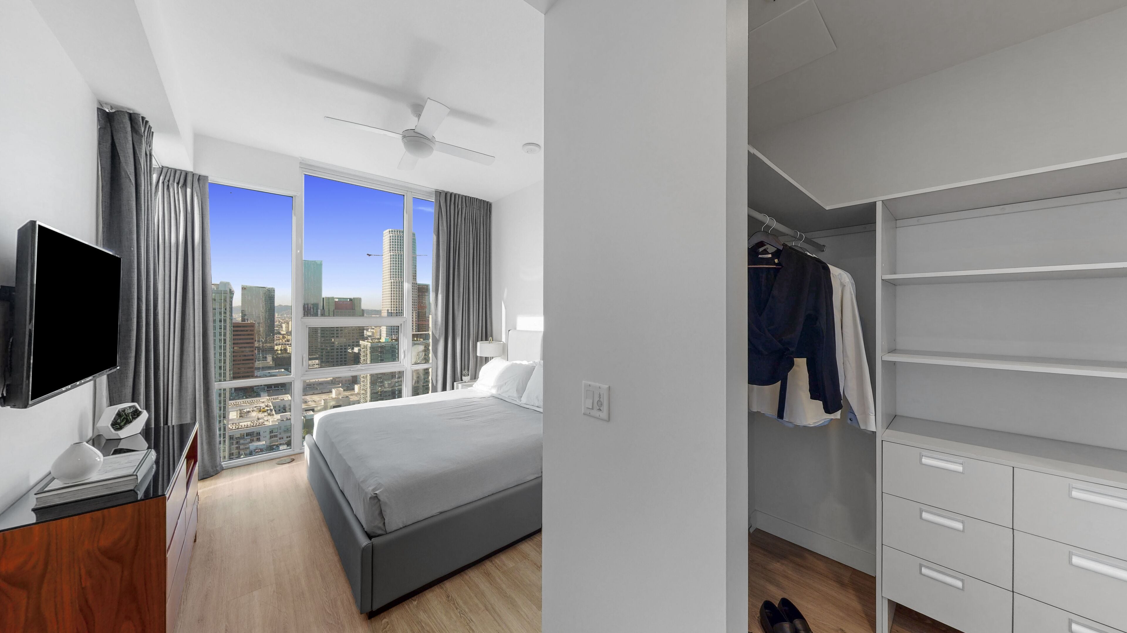 A modern hotel room with a bed, a TV, a desk, and a closet.