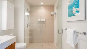 Un bagno moderno con doccia vetrata, un water bianco e un lavabo con pensile in legno.