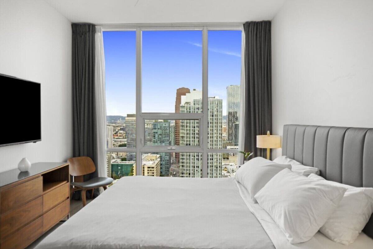Een hotelkamer met een groot raam, een bed, een bureau en een televisie.
