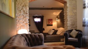Una sala de estar acogedora con un arco de piedra, un sofá y una butaca.