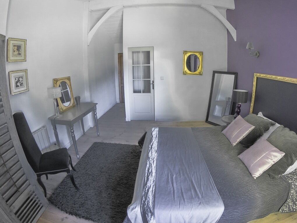 Een slaapkamer met een bed, een bureau, een stoel en een deur naar een andere kamer.