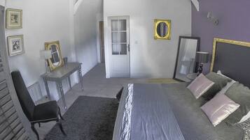 Een slaapkamer met een bed, een bureau, een stoel en een deur naar een andere kamer.