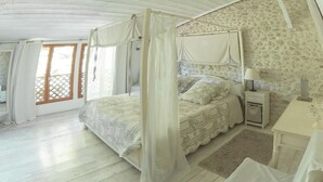 Un dormitorio con cama con dosel, una mesita de noche y un escritorio con lámpara.
