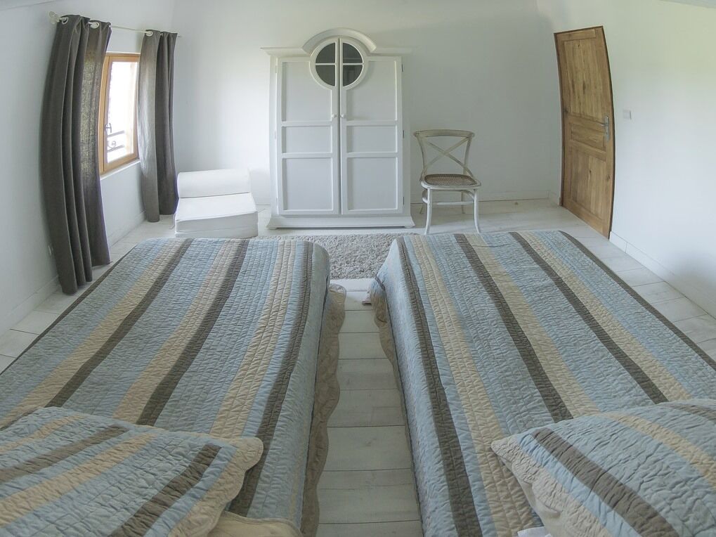 Una habitación con dos camas, un armario, una silla y una puerta de madera.