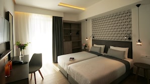Habitación de hotel moderna con una cama grande, un escritorio con silla, un televisor y una estantería.