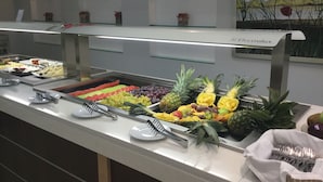 Un bufé con diversas frutas y verduras, como uvas, piña y sandía.