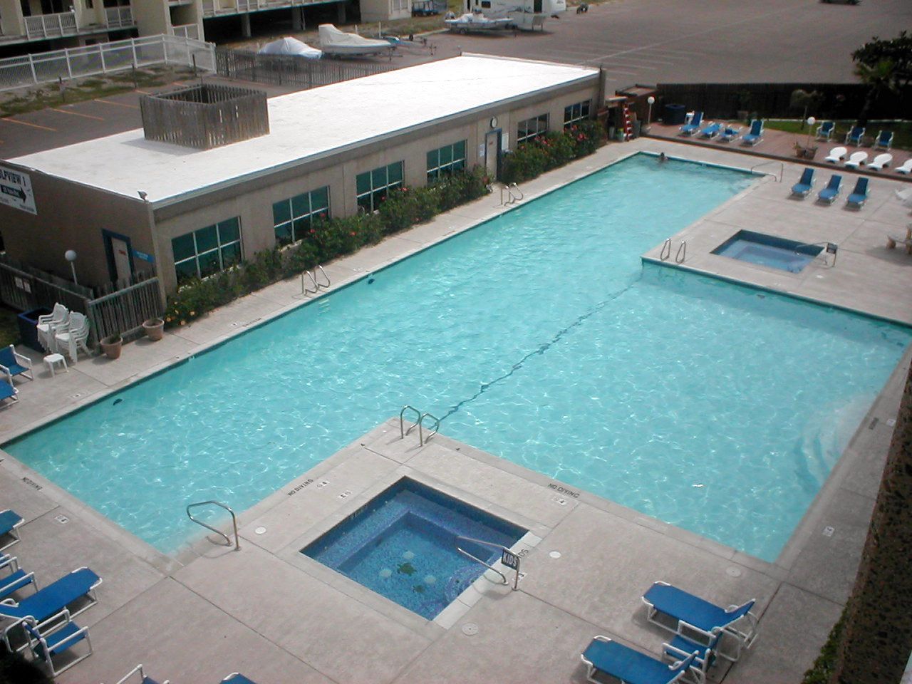 Une piscine rectangulaire dotée d’un plongeoir et entourée de chaises longues.