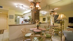 A dining area with a round glass table, wicker chairs, and a central floral arrangement.