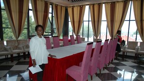 A conference room with a long table, pink chairs, and beige curtains. - Golden Chopstick Hotel (Livingstone)