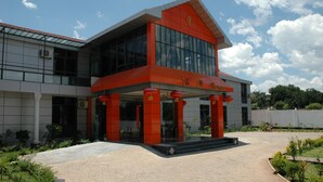 A modern building with a red and white facade, large windows, and a covered entrance area. - Golden Chopstick Hotel (Livingstone)