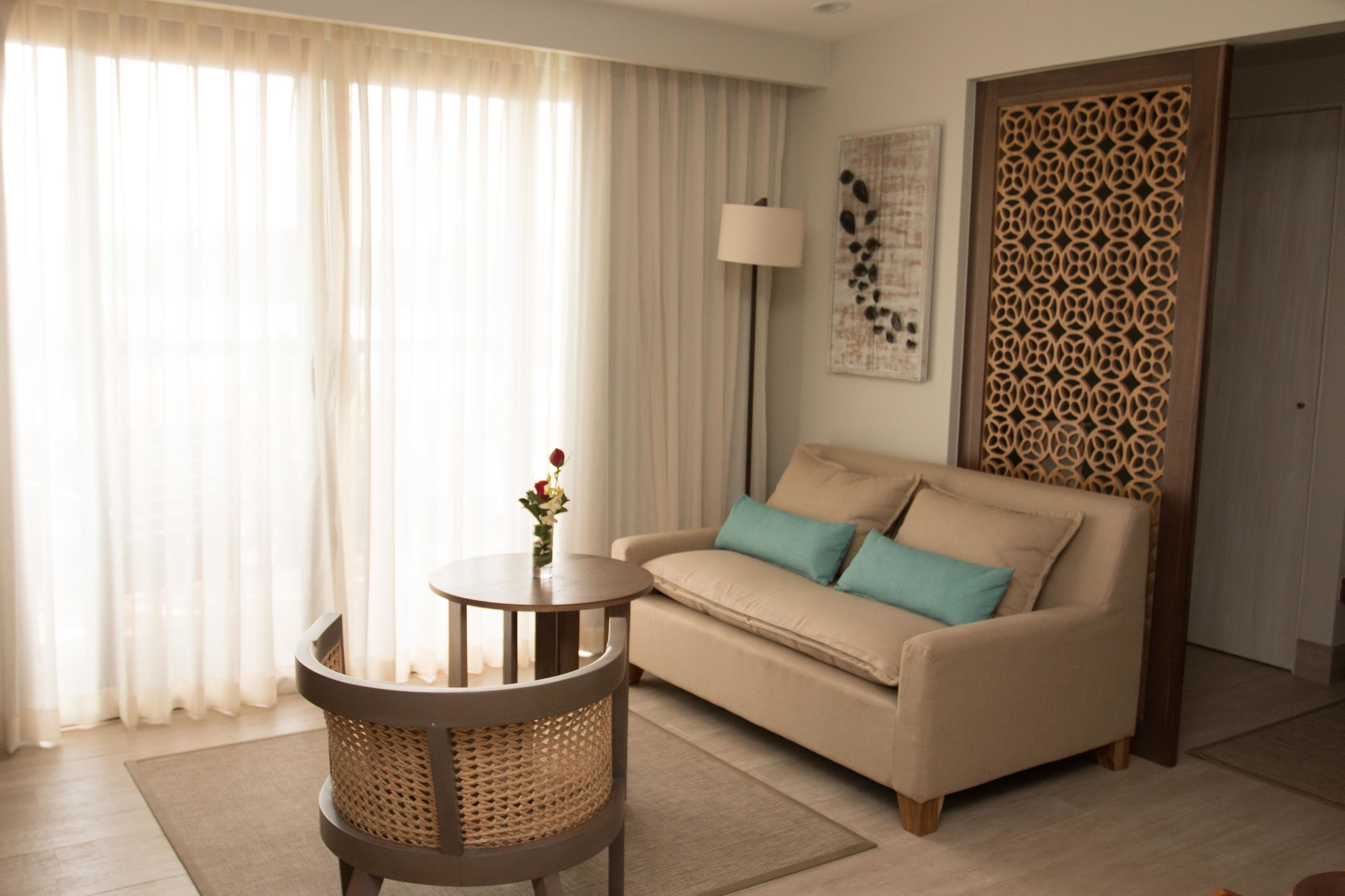 A living room with a sofa, a round table with a vase, and a patterned wall divider.