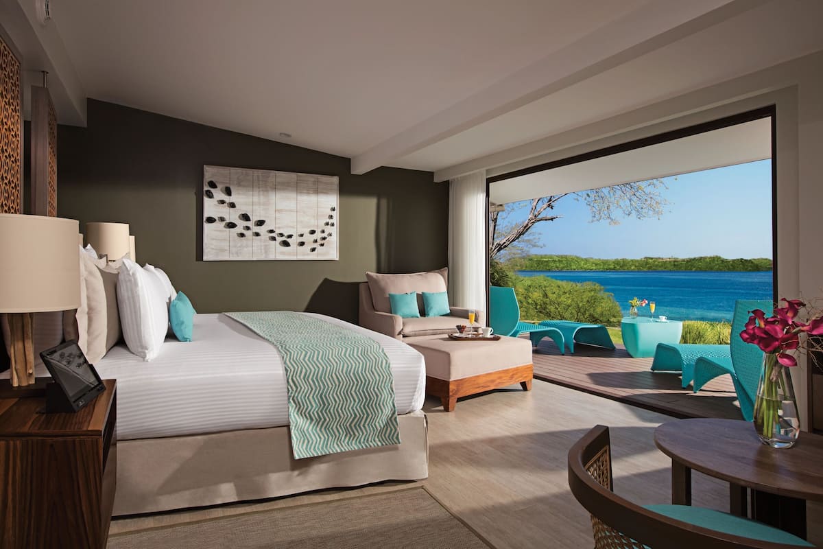 Une chambre d’hôtel moderne dotée d’un grand lit, d’un canapé, d’une table à manger et offrant une vue sur la mer.