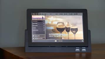 Una tableta mostrando un menú de servicios del hotel con opciones como 'Servicio a la habitación' y 'Mejoras de habitación'.