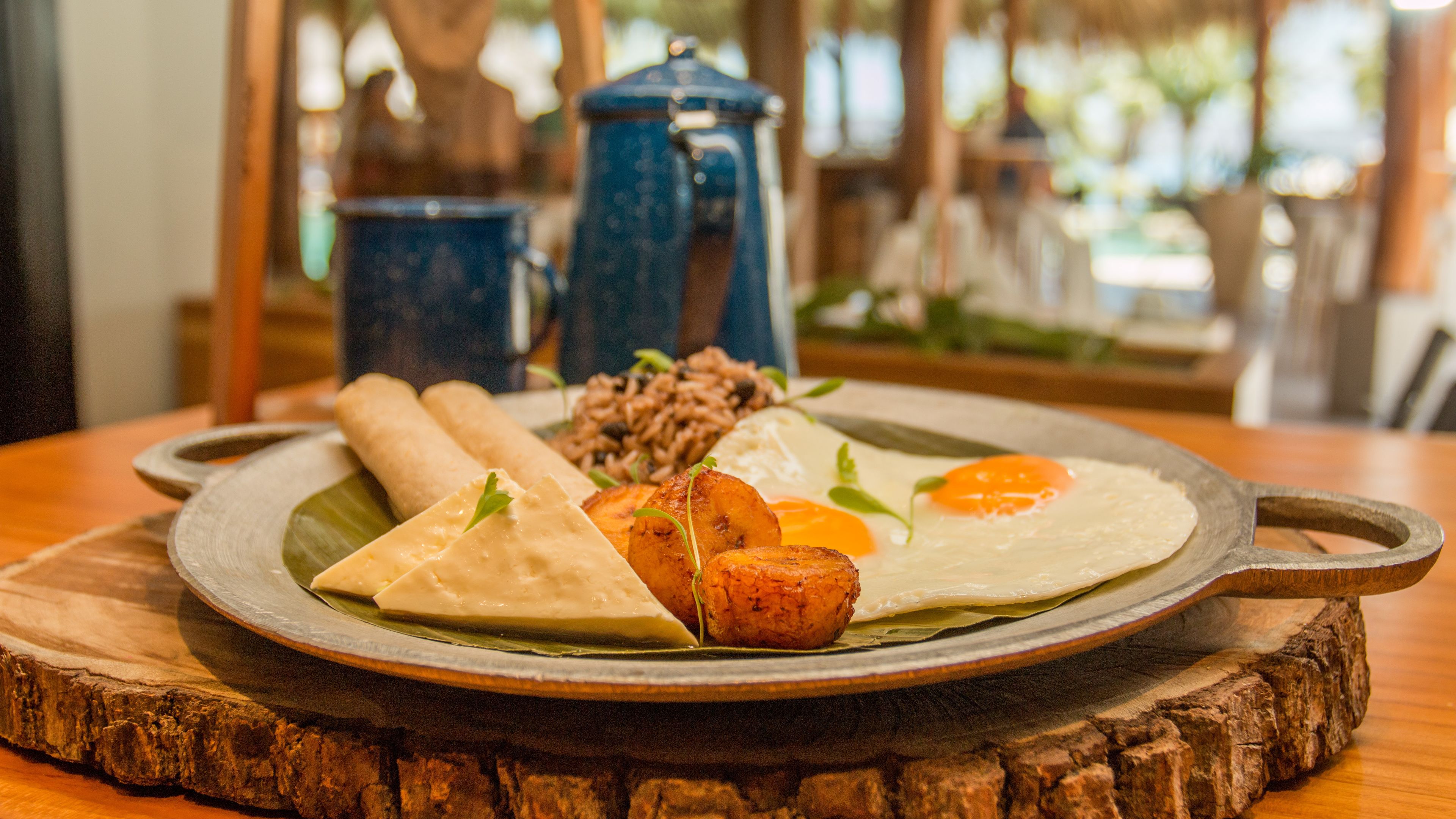 A plate of food with rice, fried plantains, and eggs on a wooden board.
